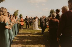 Wedding ceremony guests gathered outdoors during sunset.