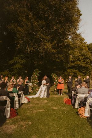 Wedding guests gathered on a grassy hillside during golden hour.