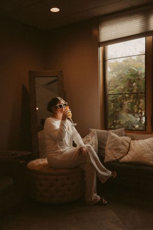 Ethereal bridal portrait by a window in a dimly lit room.