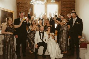 Wedding guests dance and celebrate together on a crowded dance floor at an indoor reception venue.