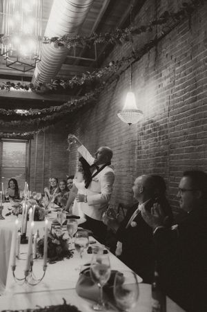 Wedding reception in a rustic brick venue with guests celebrating at long tables.