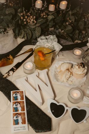 Wedding table decor with heart shapes, candles, and photographs on dark textured surface.