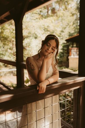 Artistic boudoir portrait of someone resting on a wooden deck railing in natural outdoor lighting.