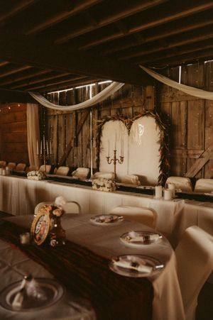 Rustic barn wedding reception setup with elegant table settings and draped fabric decor.