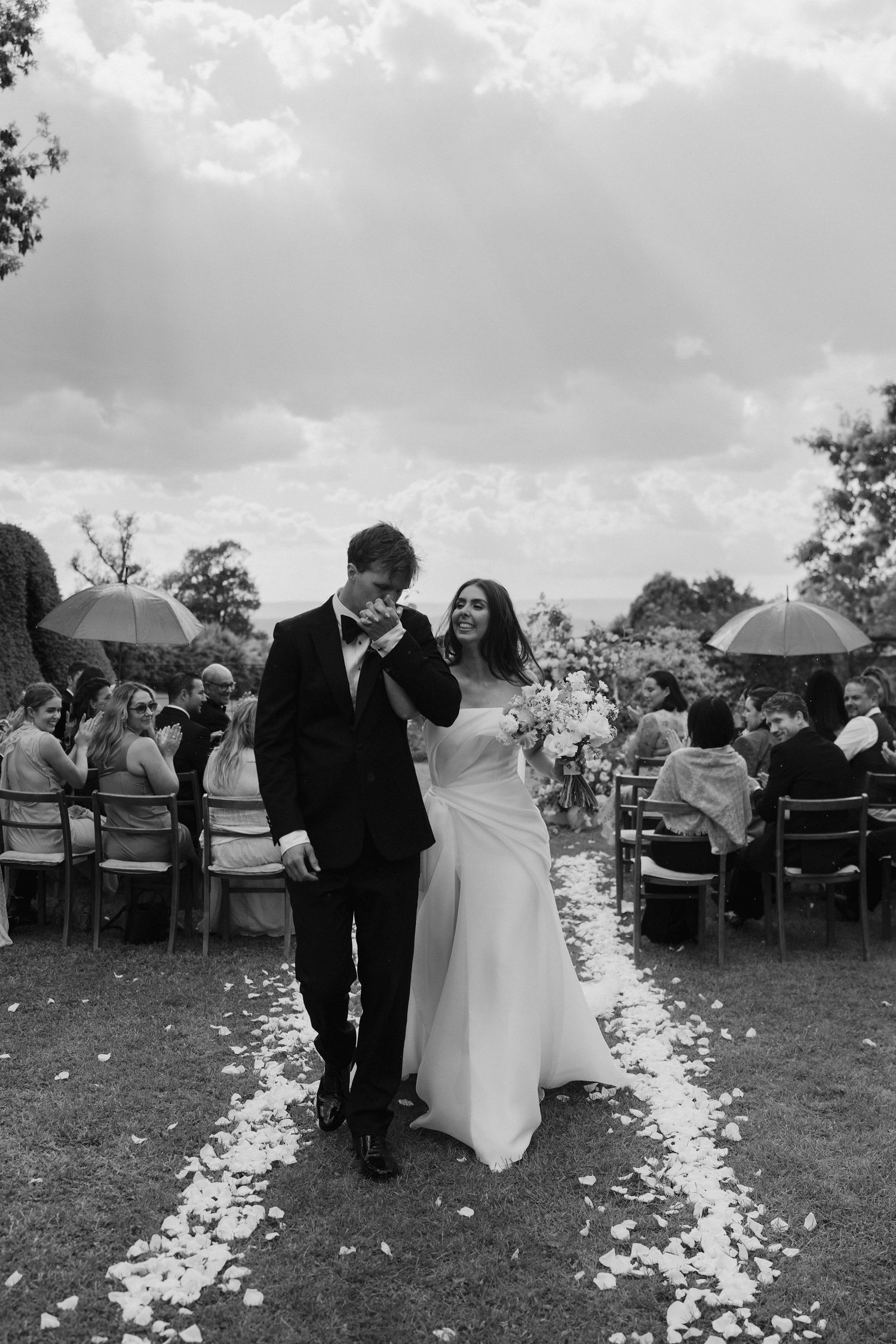 groom kissing brides hand as they exit their wedding ceremony at dewsall court in herefordshire