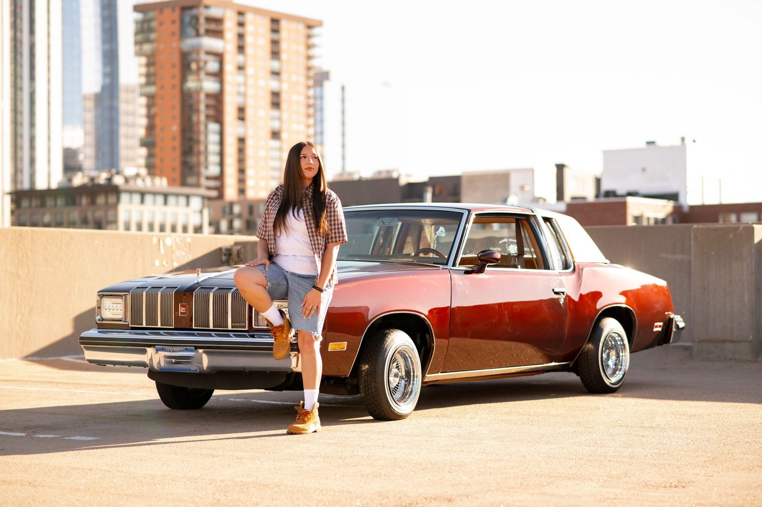 Classic red Pontiac sedan parked on urban rooftop with city buildings in background.