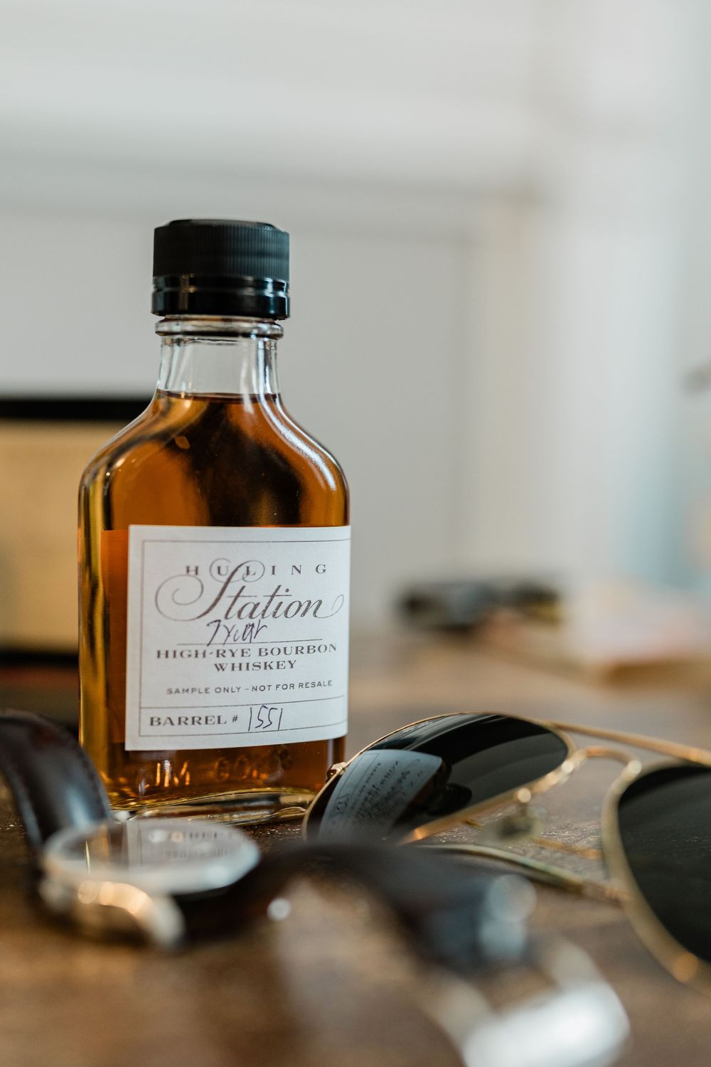 Glass bottles of brown liquid with elegant handwritten labels sit on a wooden surface.