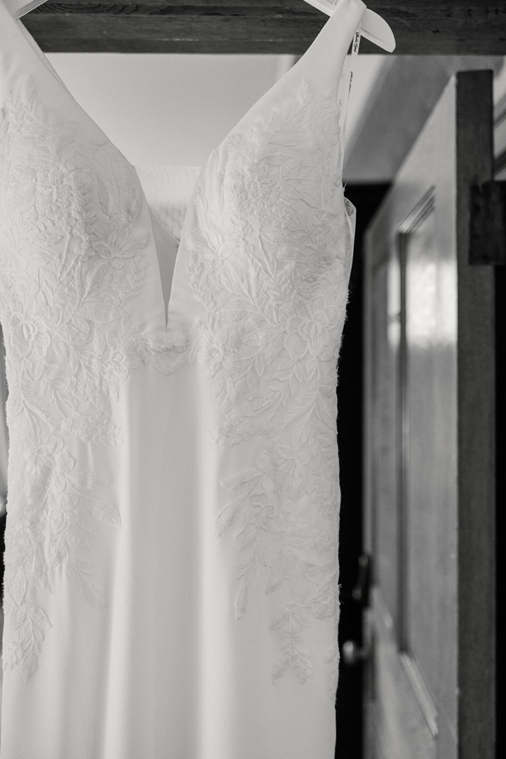 Close-up details of delicate white lace wedding dress bodices hanging in a row.