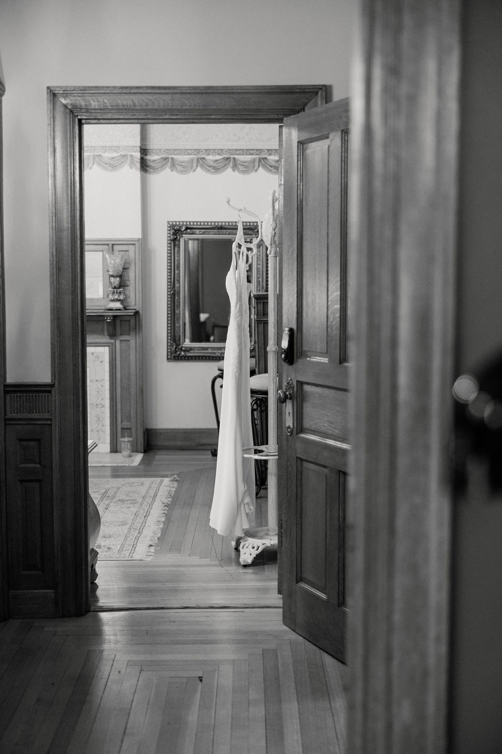 Long hallway with wooden floors and dark doors in an elegant historic building.