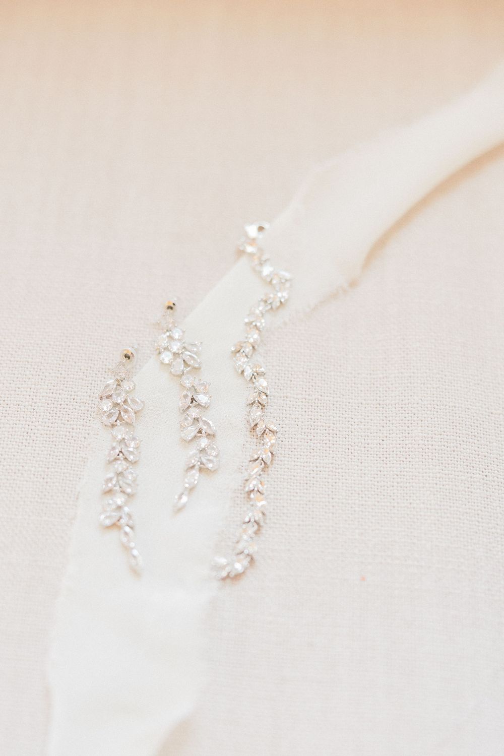 Delicate pearl and crystal floral bridal hair accessories arranged on white fabric.