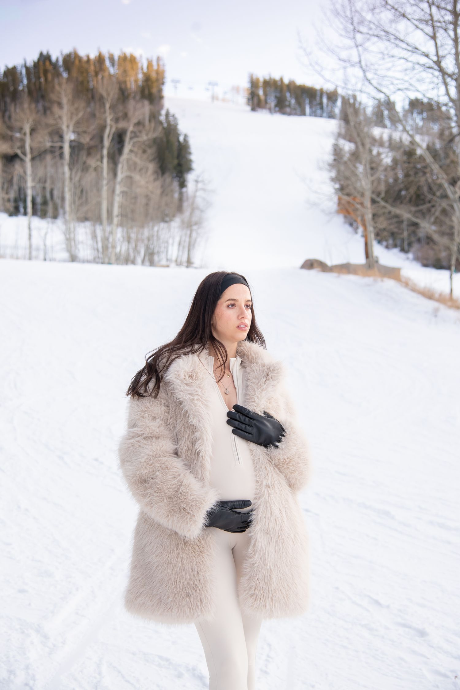 Vail Colorado maternity photo session on the ski slopes with snow and mountains in the background and woman in a stylish outfit