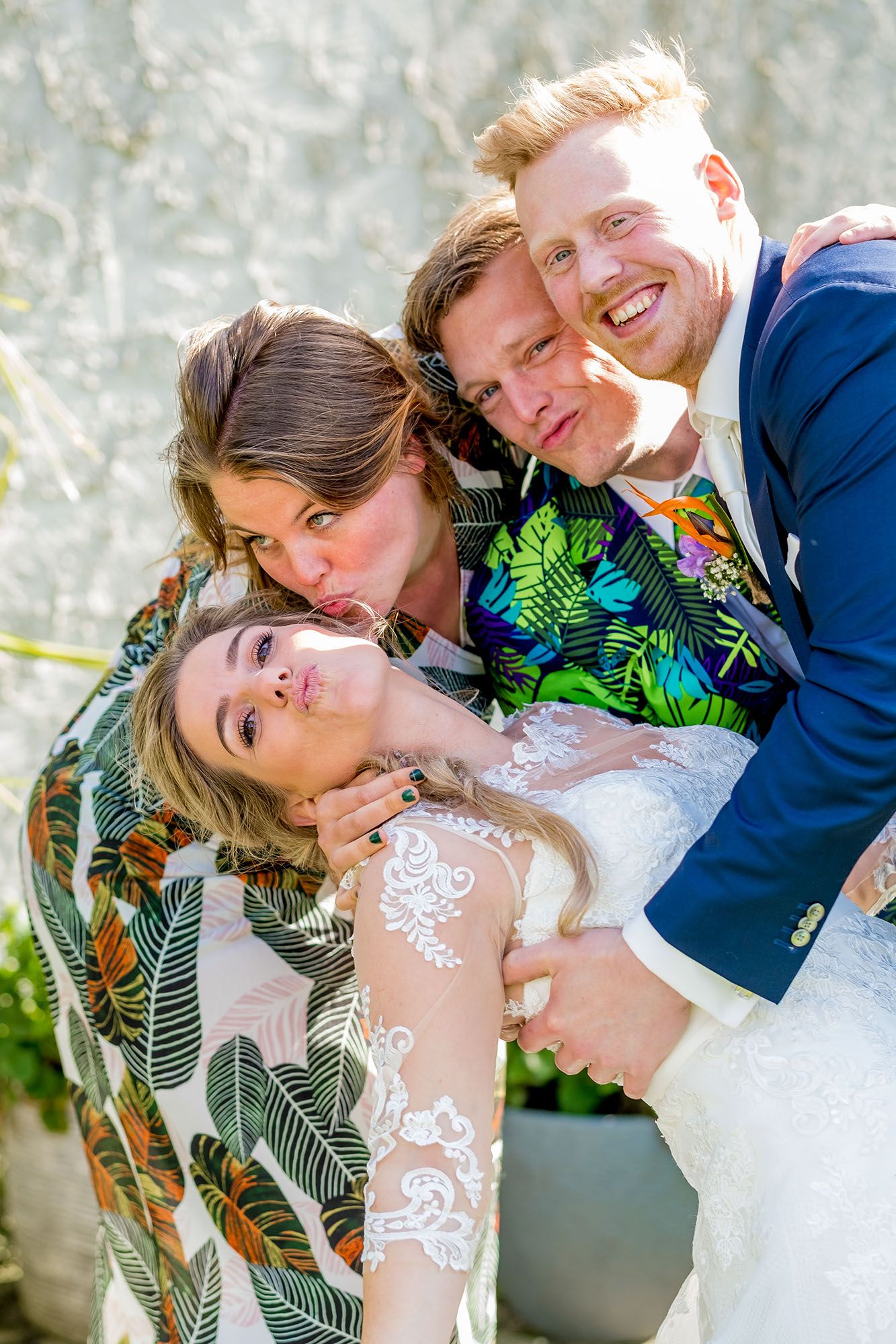 A couple in wedding attire share romantic poses together in a garden setting with tropical greenery.