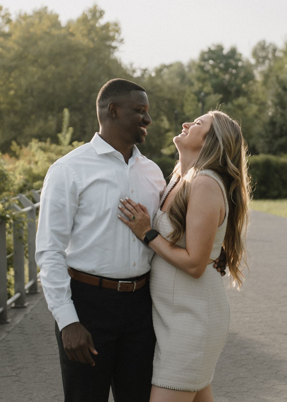 A joyful couple embraces and laughs together on a park pathway.