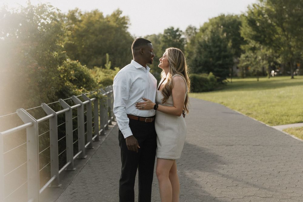A couple shares an intimate moment while standing on a park path during golden hour.