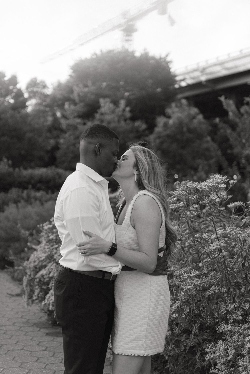 A romantic black and white photo of a couple sharing an intimate moment in a garden setting.