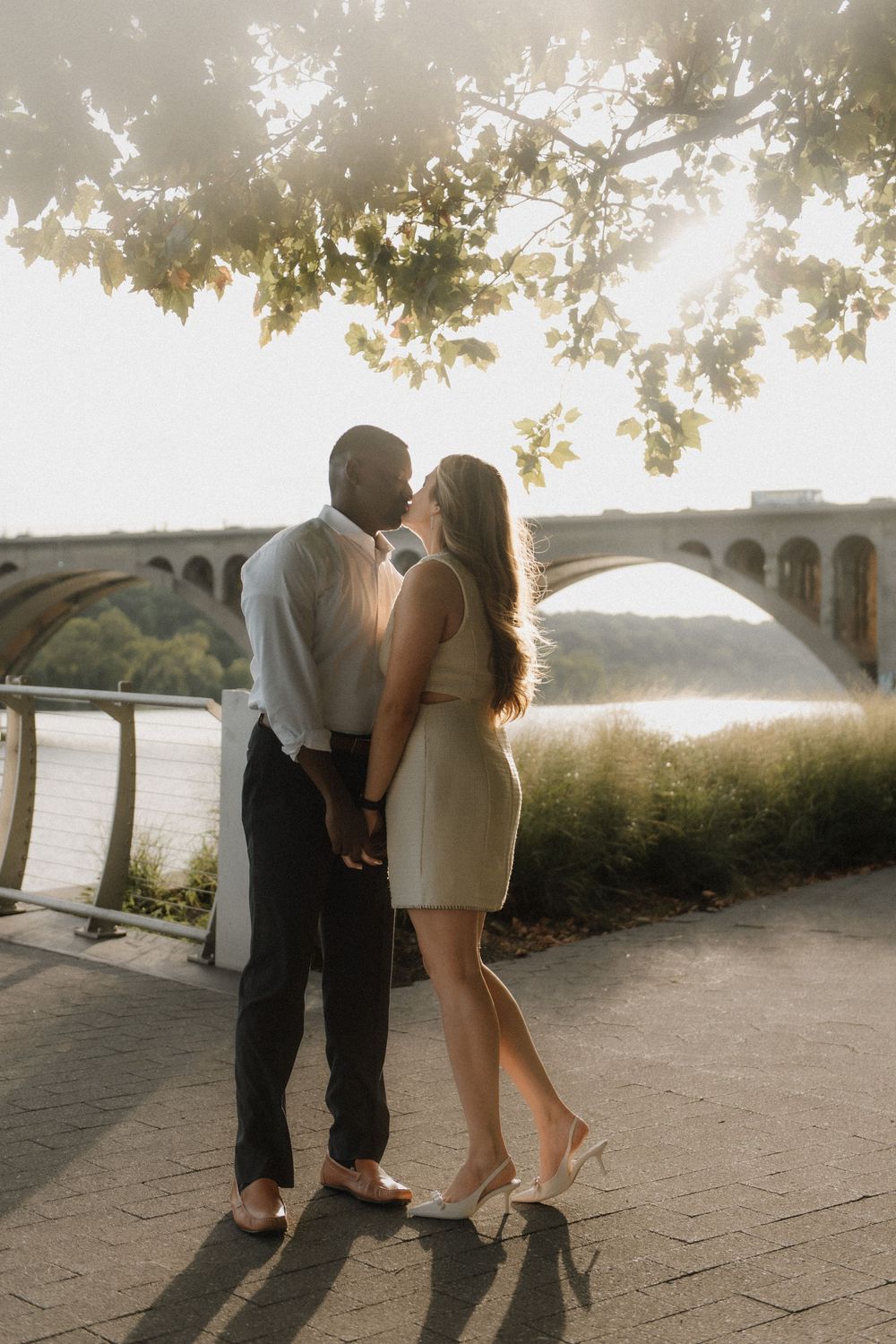 Couple dances together on stone path during golden hour by waterfront.