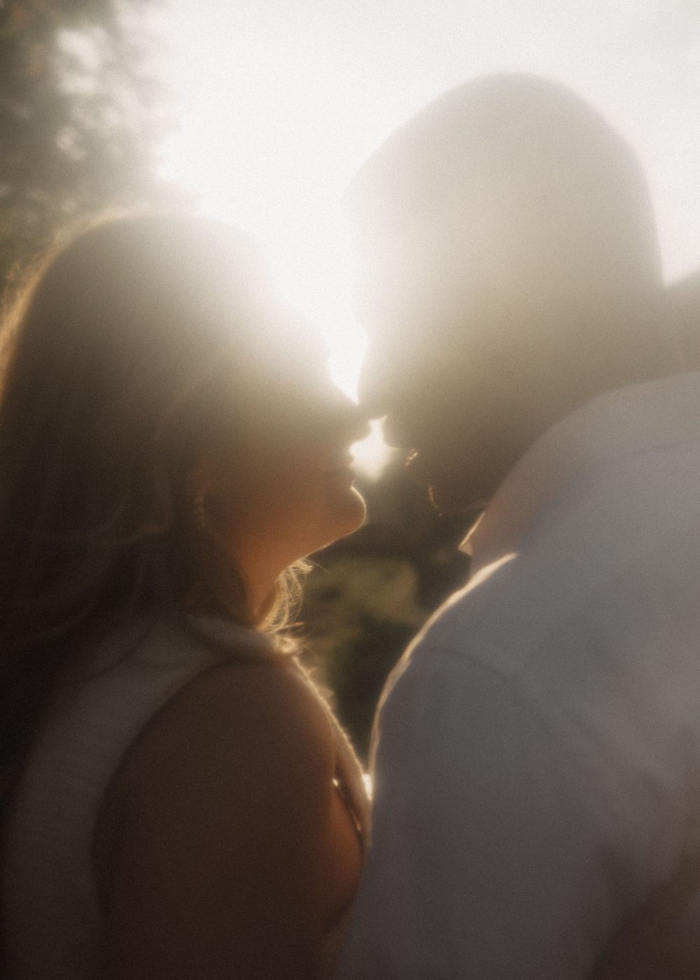 A backlit silhouette of a couple in an intimate moment during golden hour.