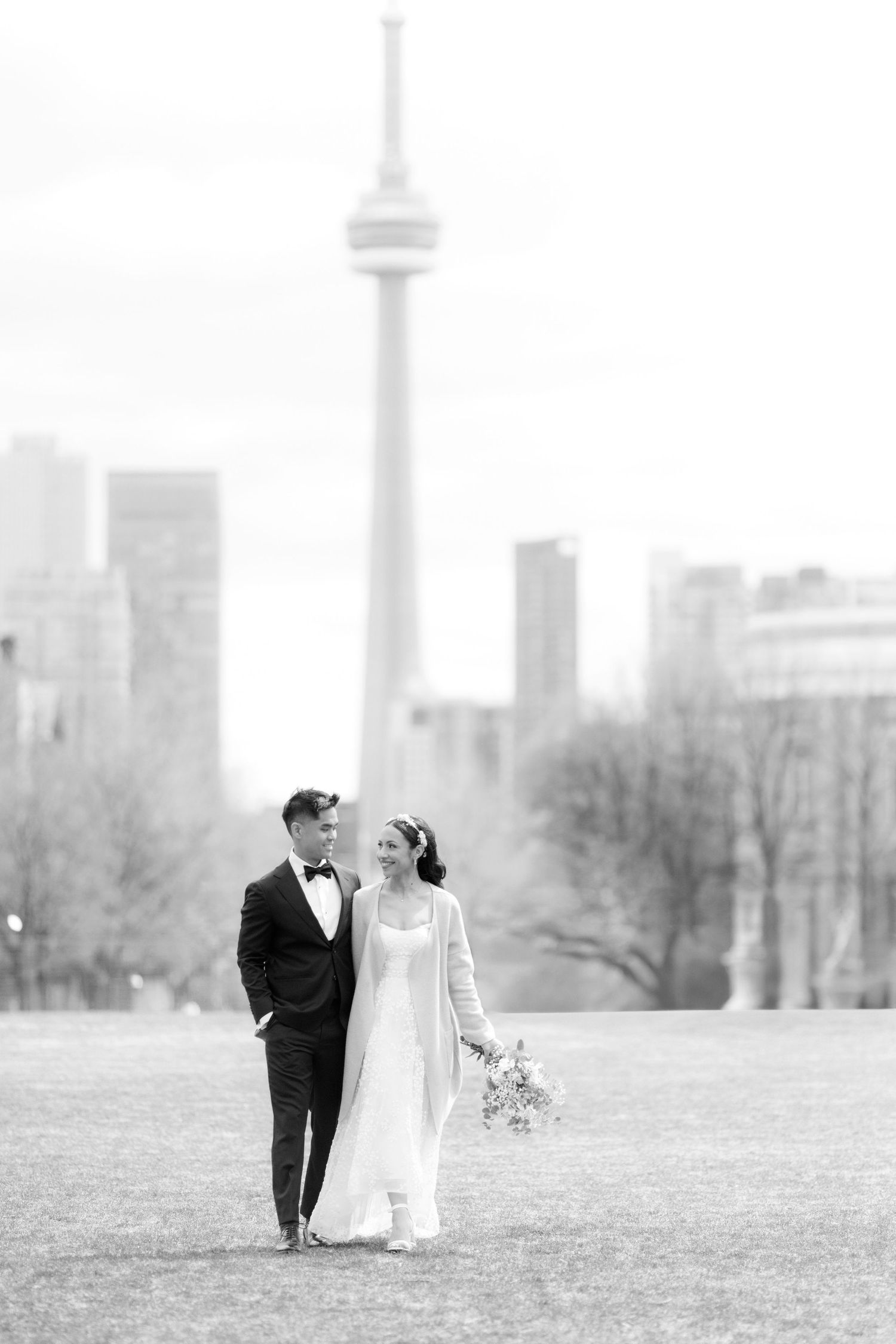 Wedding couple walks down the aisle at an indoor ceremony decorated with white chairs and dandelion-like light fixtures.
