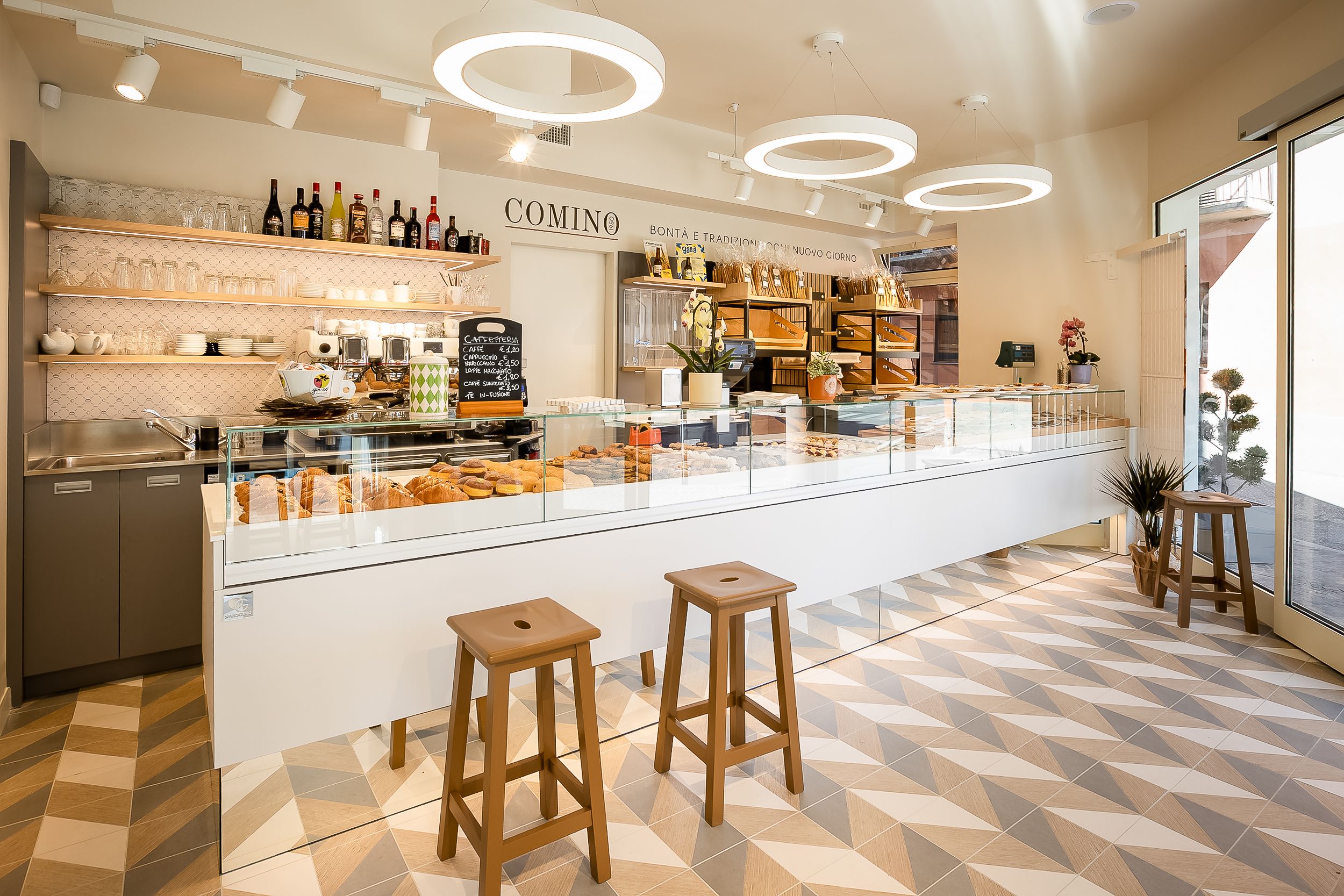 Modern bar interior with circular ceiling lights, wooden stools and clean minimalist design.