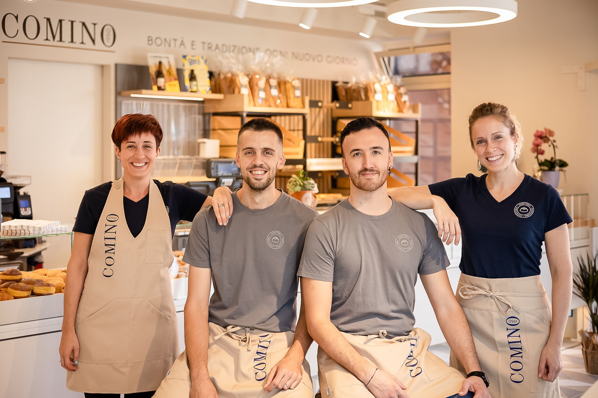 Restaurant staff members in gray uniforms stand together in a modern dining establishment with a warm ambiance.