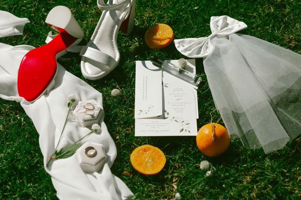 A still life composition of oranges and red apples arranged with white fabric on green grass in natural light.
