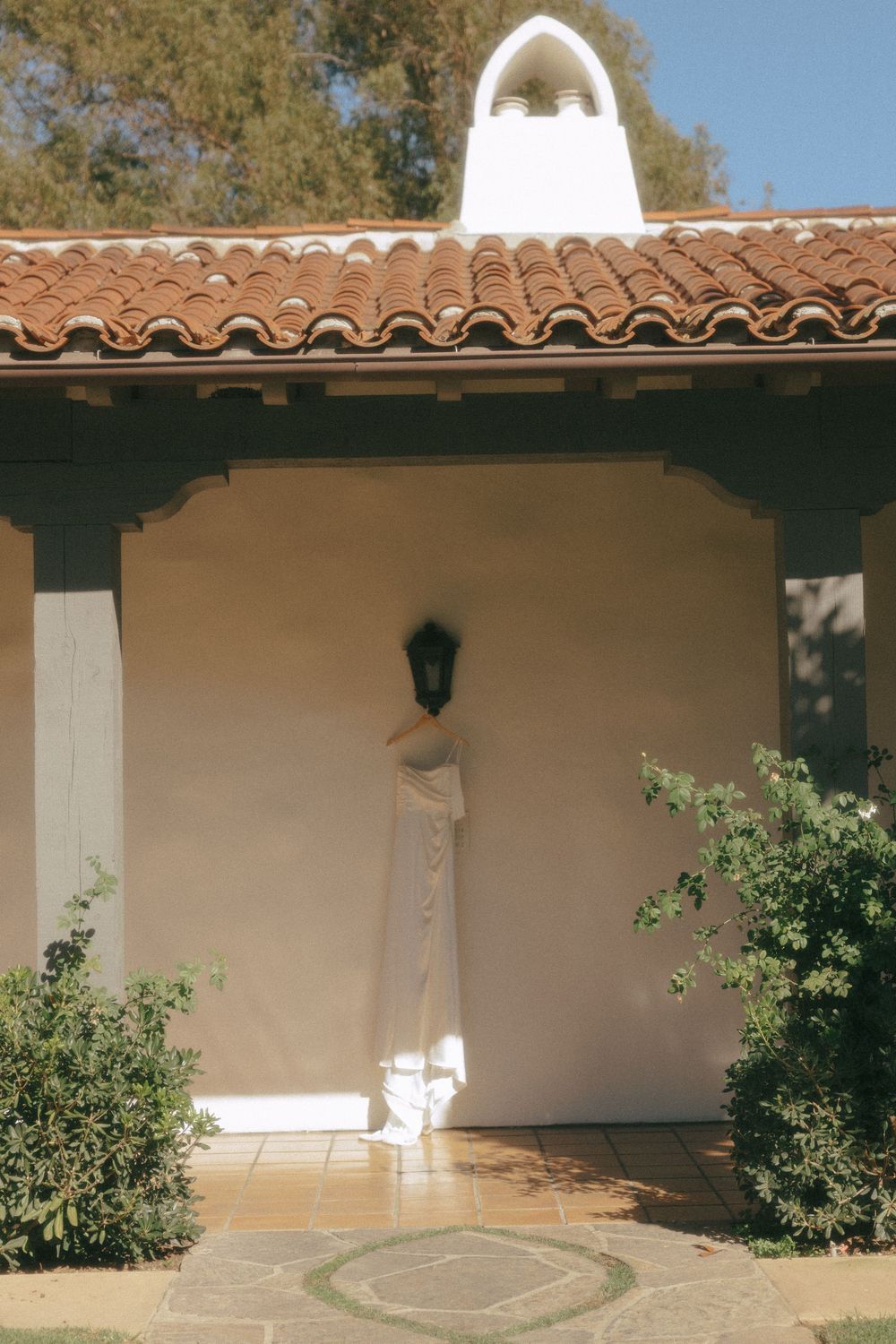 Spanish colonial style courtyard with white stucco walls, terracotta tile roof, and landscaped garden elements.