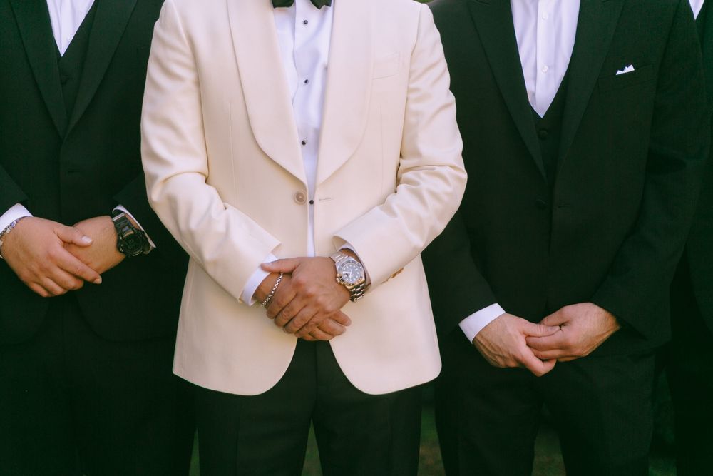 A group of people wearing formal attire with white and black tuxedo jackets standing together.