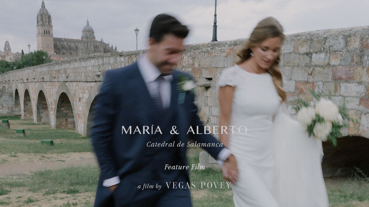 A romantic garden wedding scene with guests gathered in the background during a tender kiss moment.