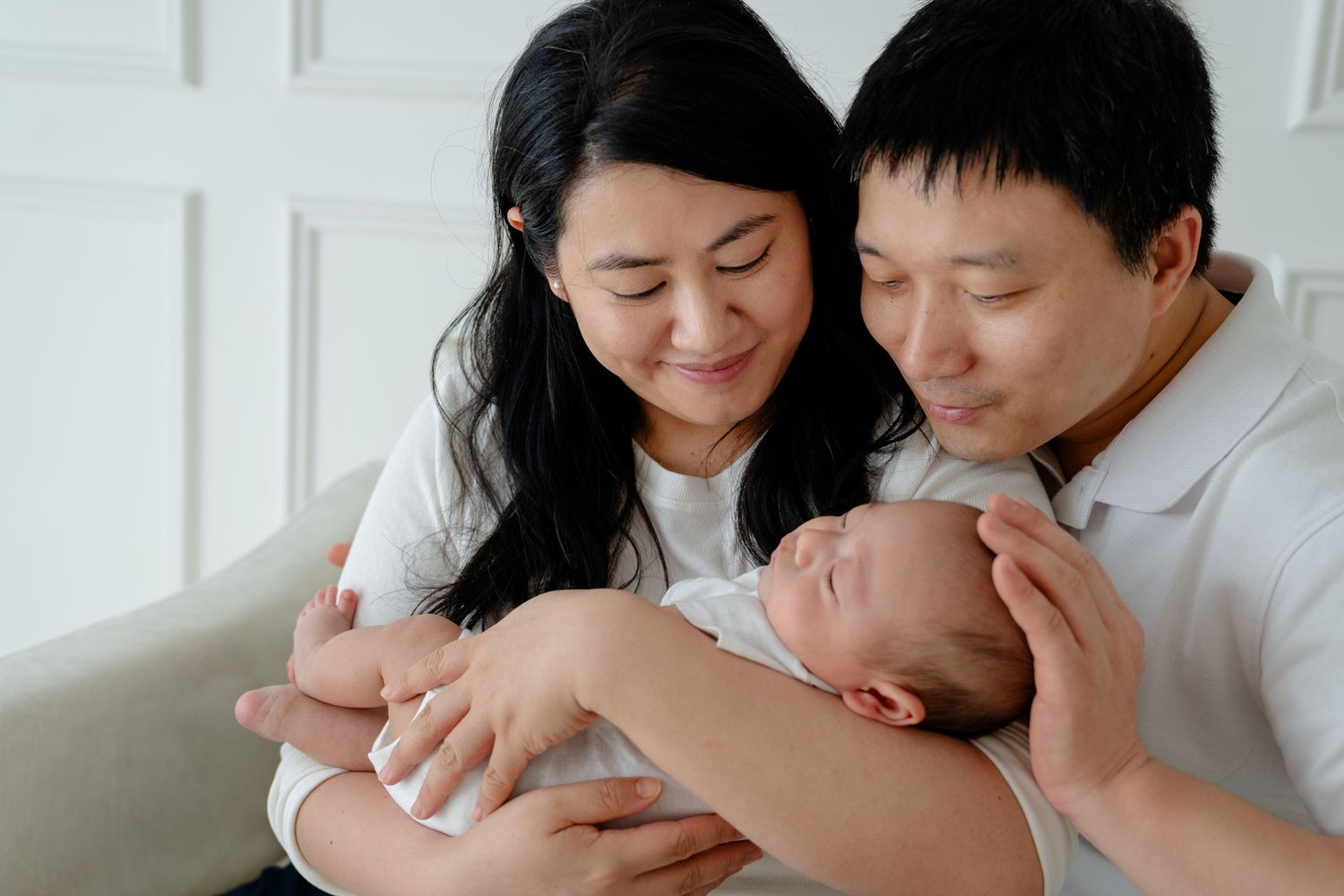 A tender family moment captured in black and white showing loving interaction with a newborn baby.