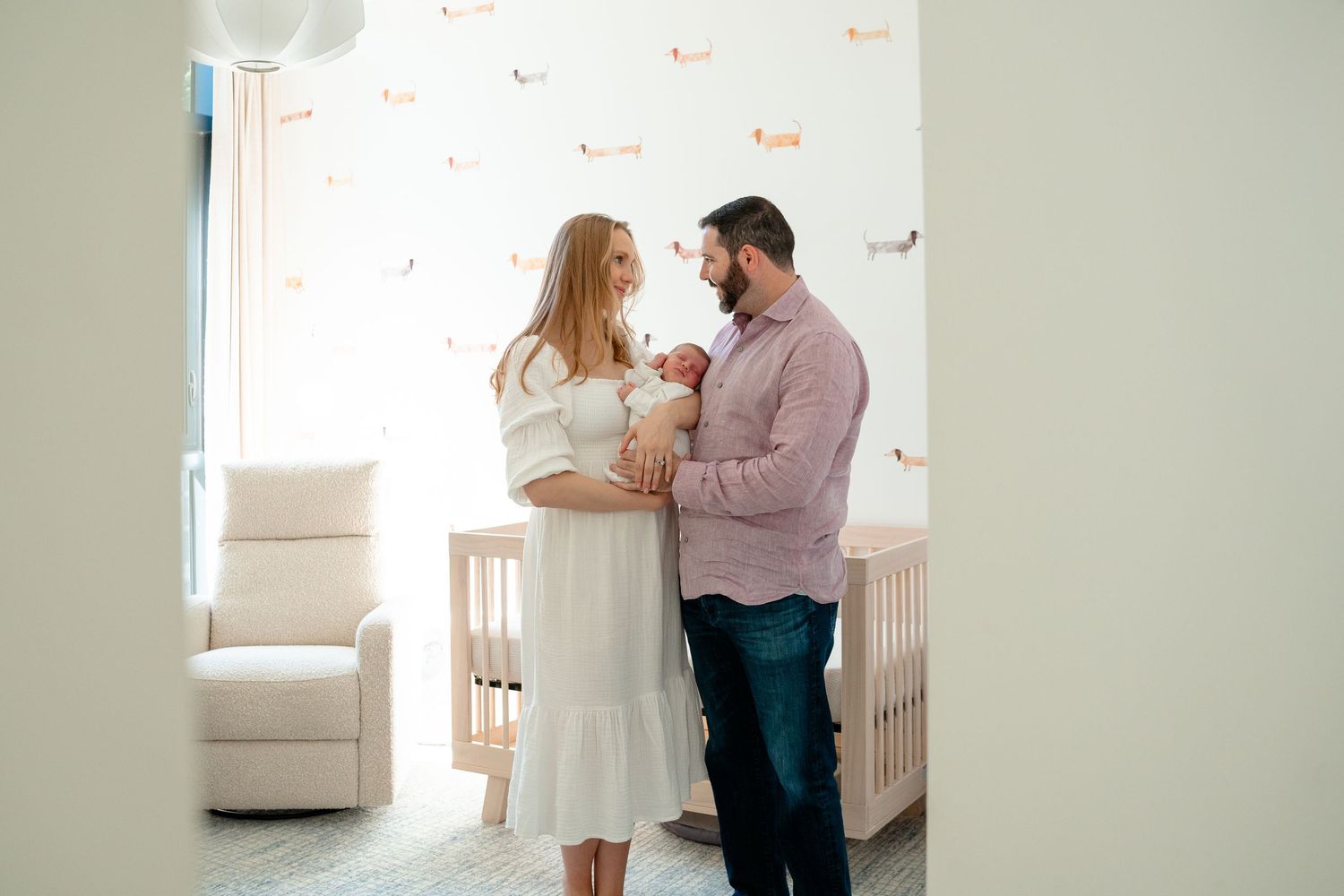 A couple in soft natural light shares an intimate moment together in a bright white room.