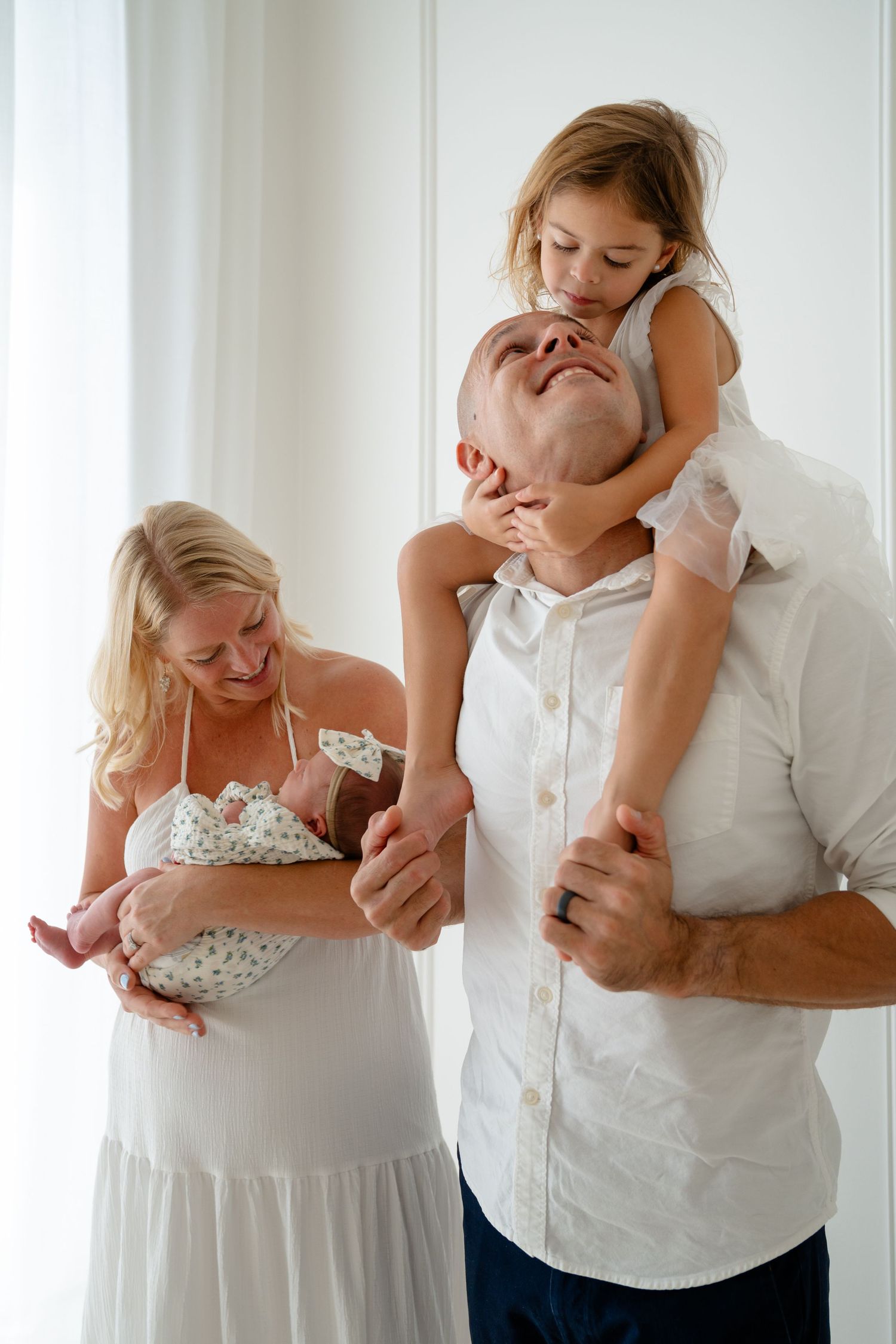 A series of tender moments between parent and child in white clothing against a light background.