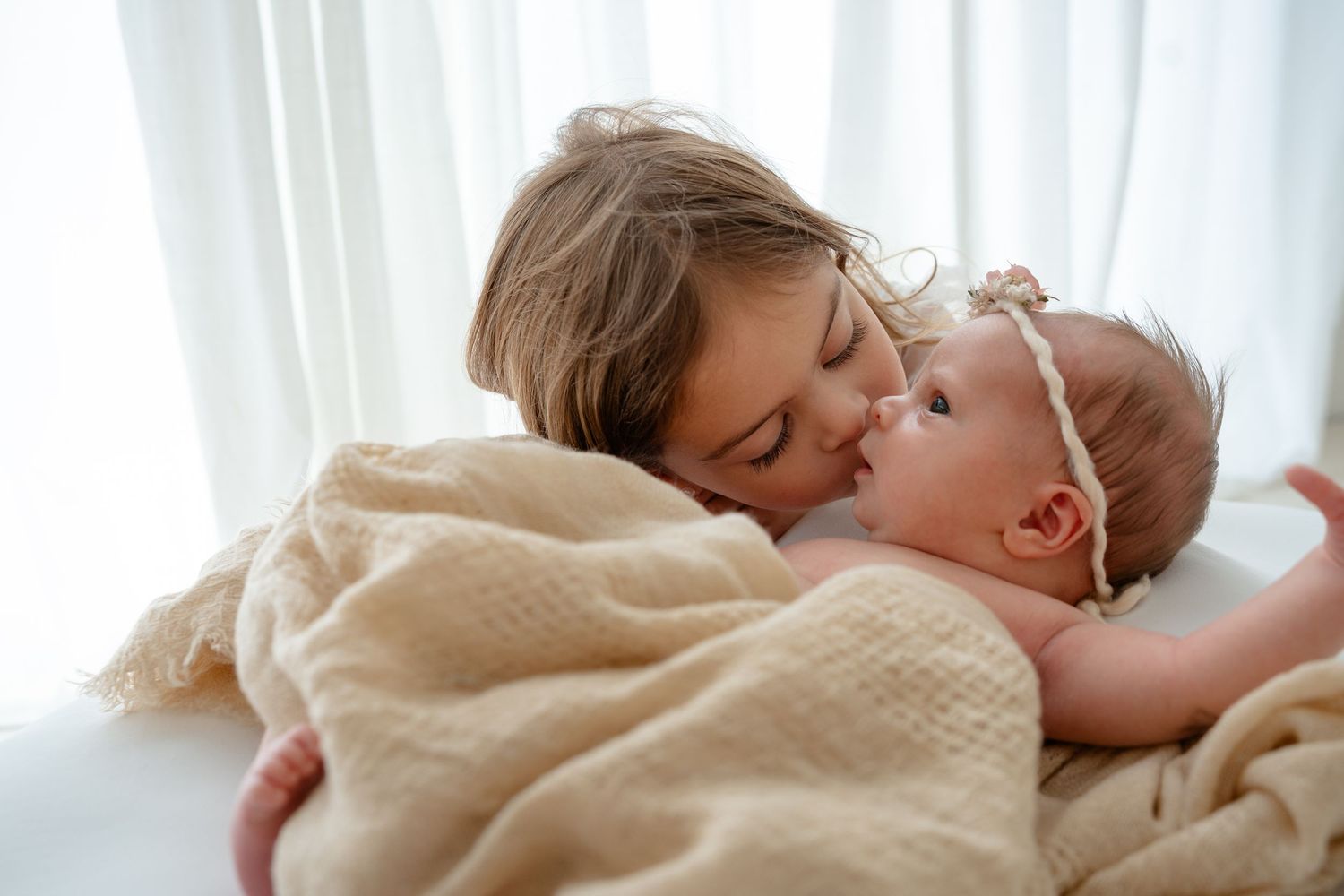Series of tender moments showing parent and baby interacting on white bedding.