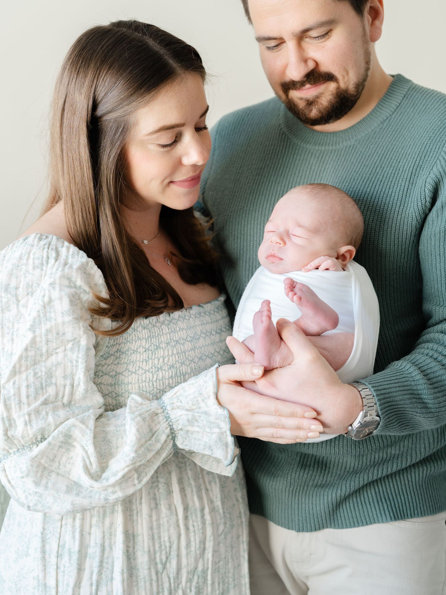 Parents cuddling newborn in home during lifestyle newborn photography session in Monmouth County.