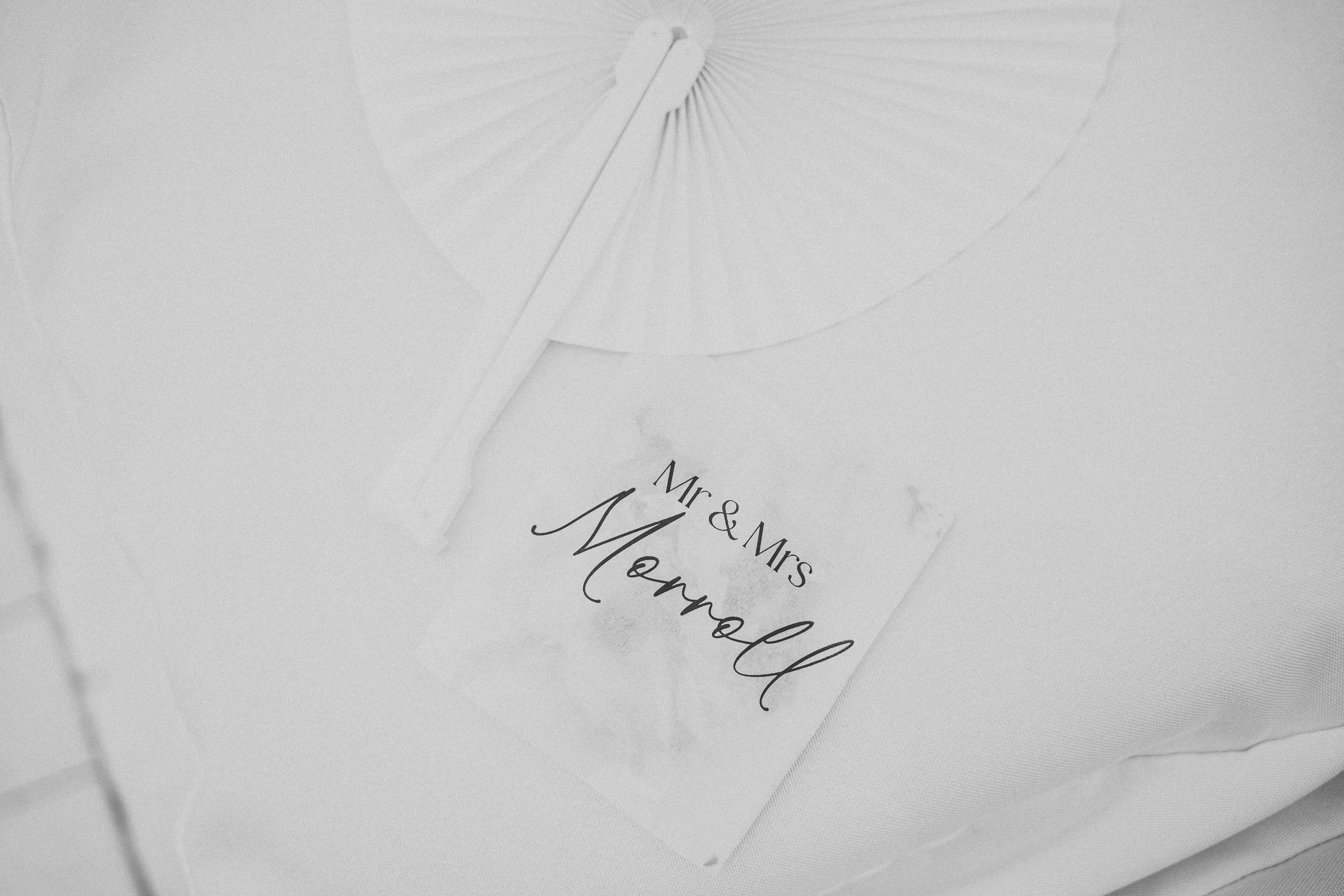 Close-up view of white cotton fabric with elegant embroidered monogram lettering in light thread.
