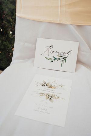 Elegant wedding invitation suite with calligraphy and delicate floral designs on white paper against a cream background.