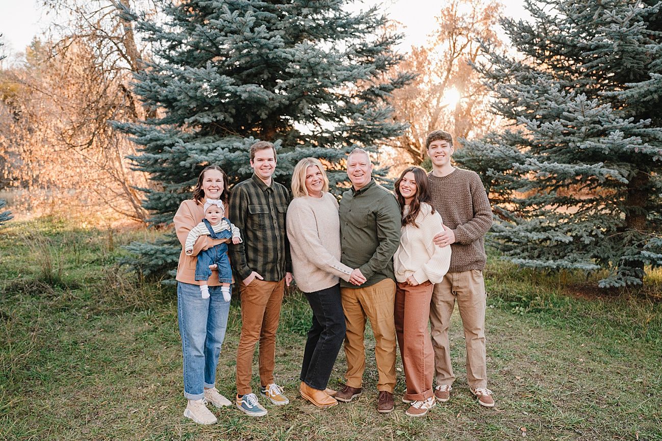 Family portrait session near blue spruce trees during golden hour with natural lighting.