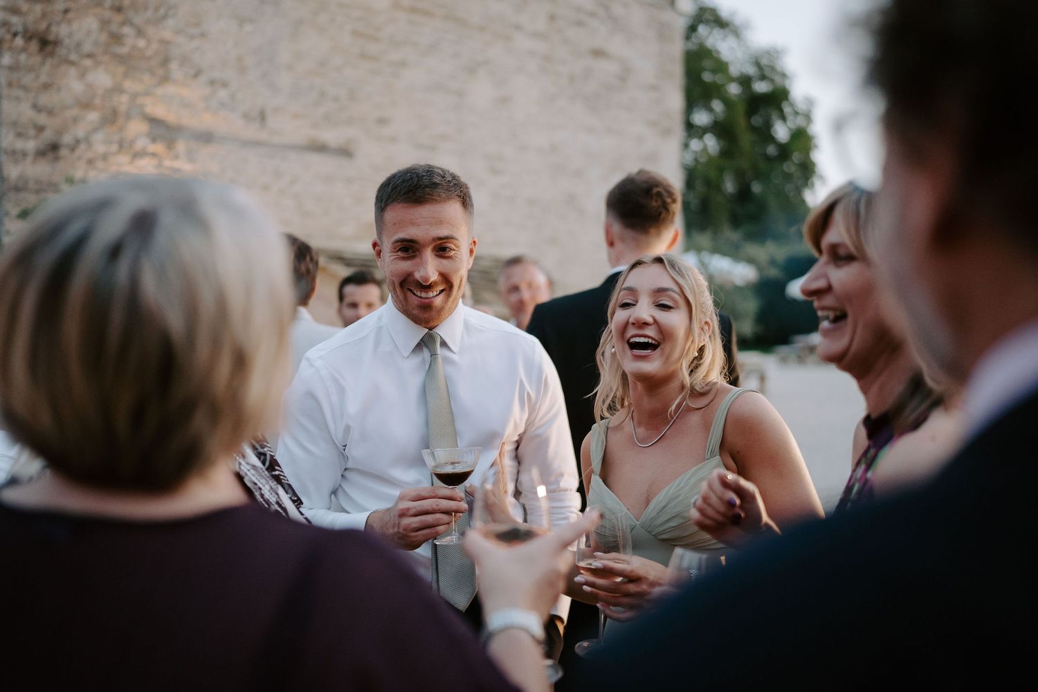 wedding guests laughing during cocktail hour at ivy lodge wedding in cirencester