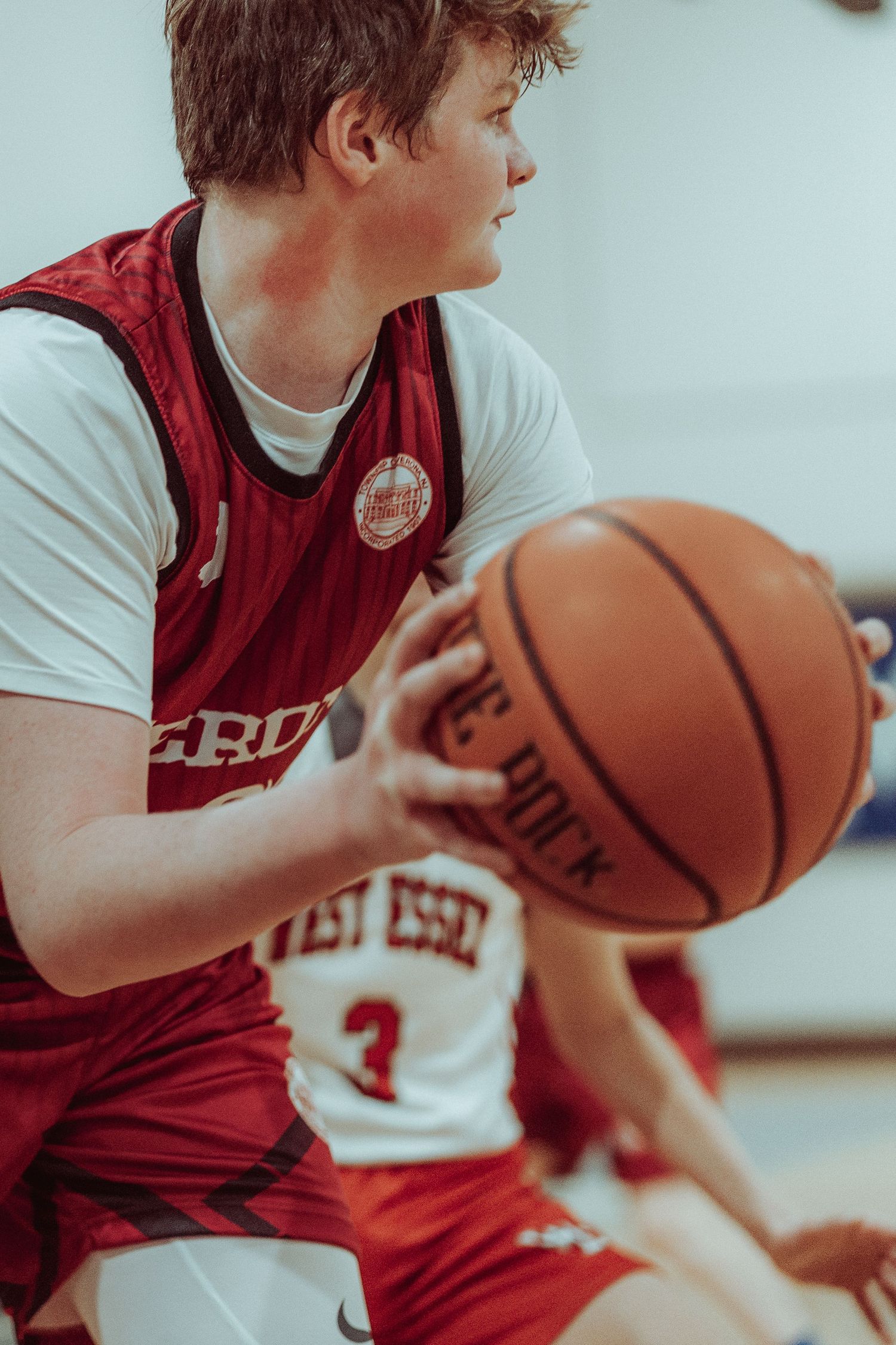 Basketball player in red jersey dribbles ball during game in gymnasium.