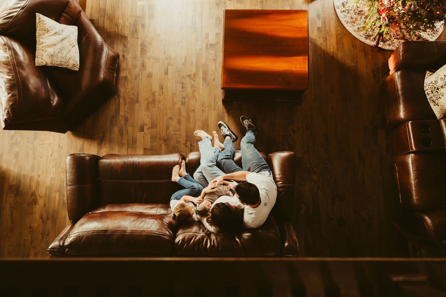 Couple cuddling on leather sofa viewed from above in warm cozy living room setting.