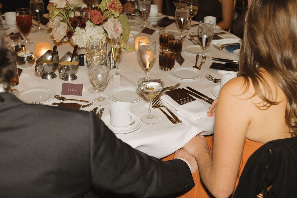 Elegant table settings at a formal dinner event with white tablecloths, wine glasses, and place settings.