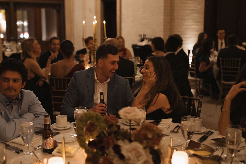 Guests seated at elegant dining tables during a formal evening reception with warm lighting and table settings.