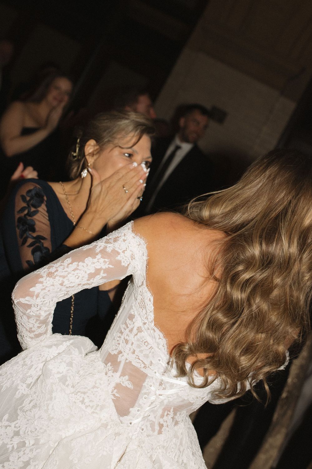 Dancing couple in elegant attire share an intimate moment on a dimly lit dance floor at a formal event.