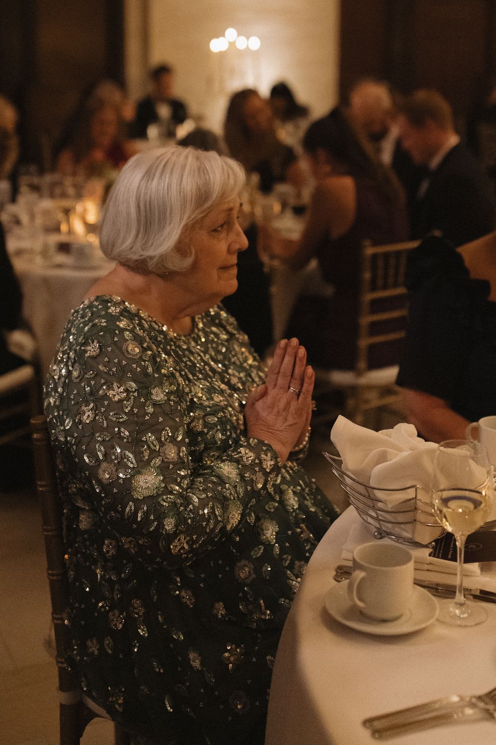 Guest in a sparkly evening gown seated at an elegant wedding reception table.