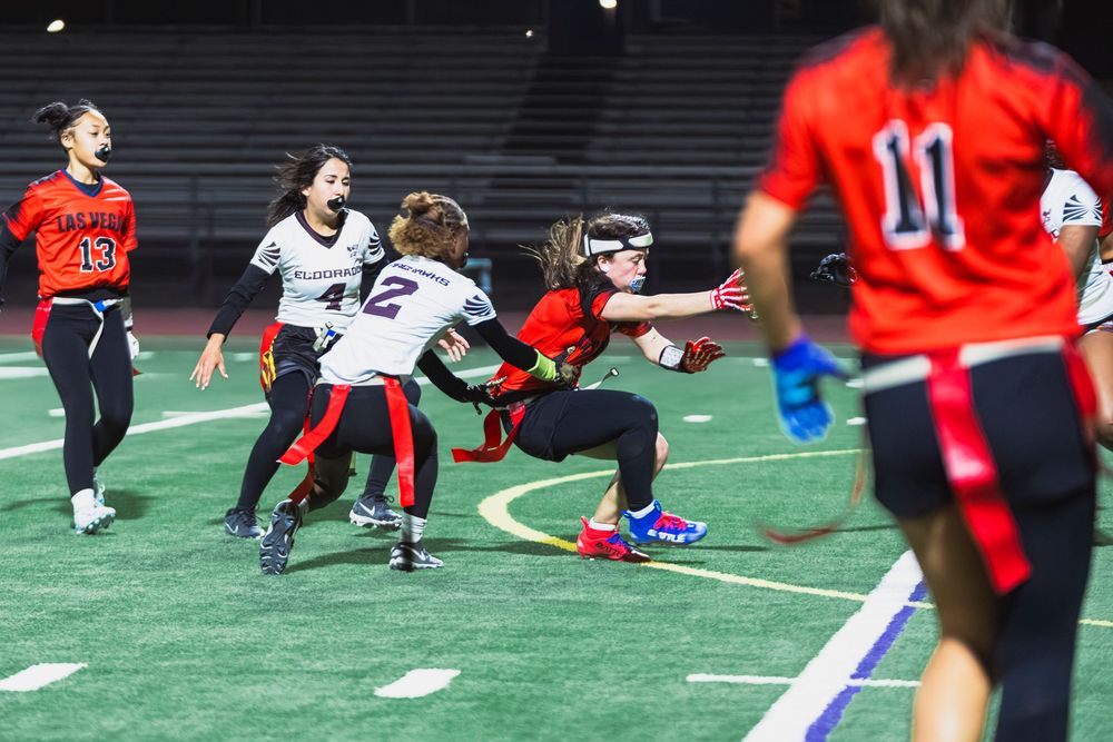 Girls flag football player evading defensive players by dropping
