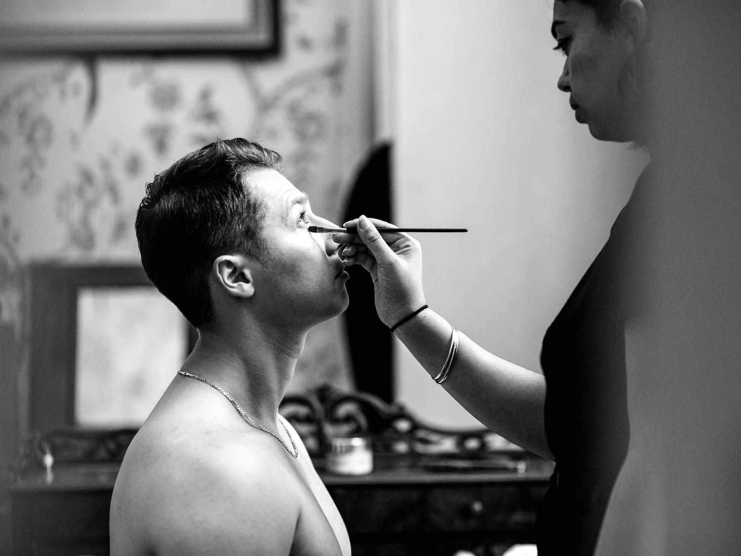 Black and white photo sequence showing someone getting their face painted or makeup applied in four progressive steps.