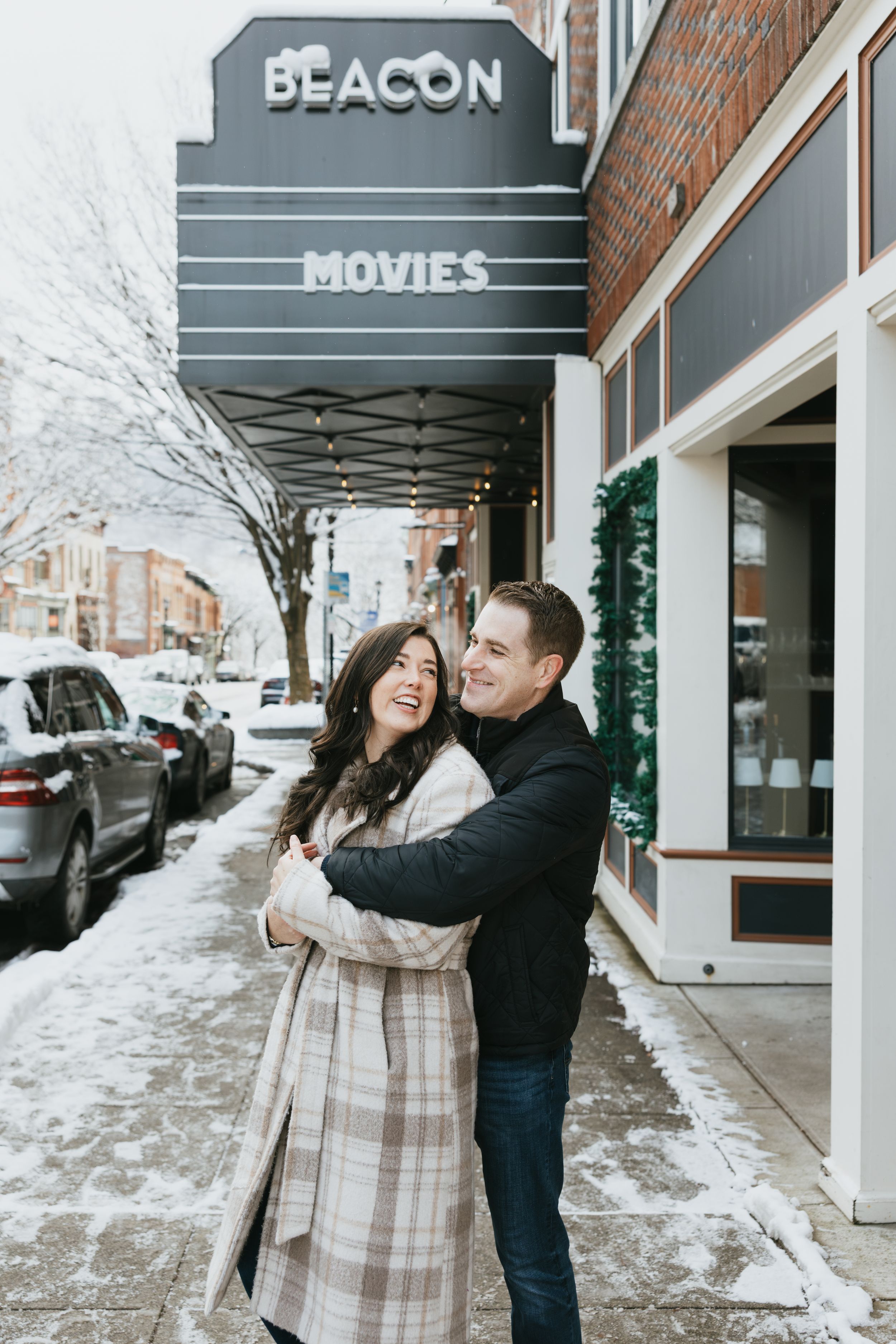 A couple shares a romantic moment outside a movie theater on a snowy winter day.