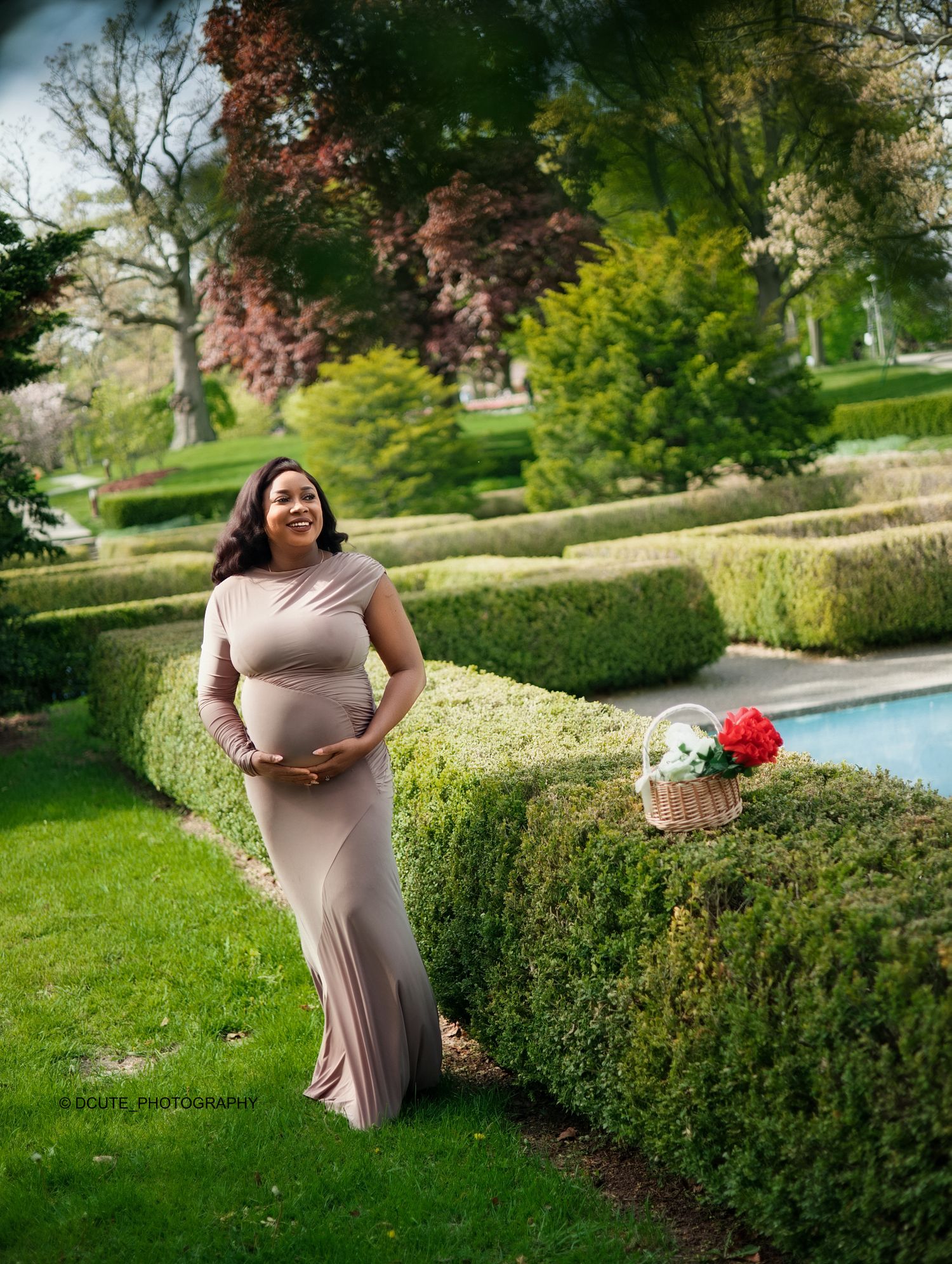 Pregnant woman in champagne silk draped fabric cradling baby bump in a minimalist studio.