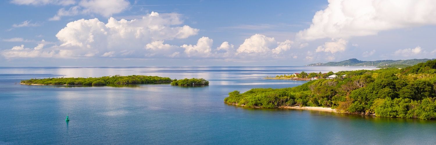 Aerial panorama of tropical coastline with turquoise waters and lush islands.
