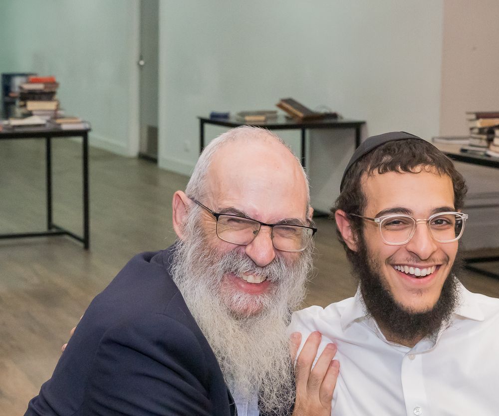 Two people sharing a joyful moment while sitting together in an office setting.