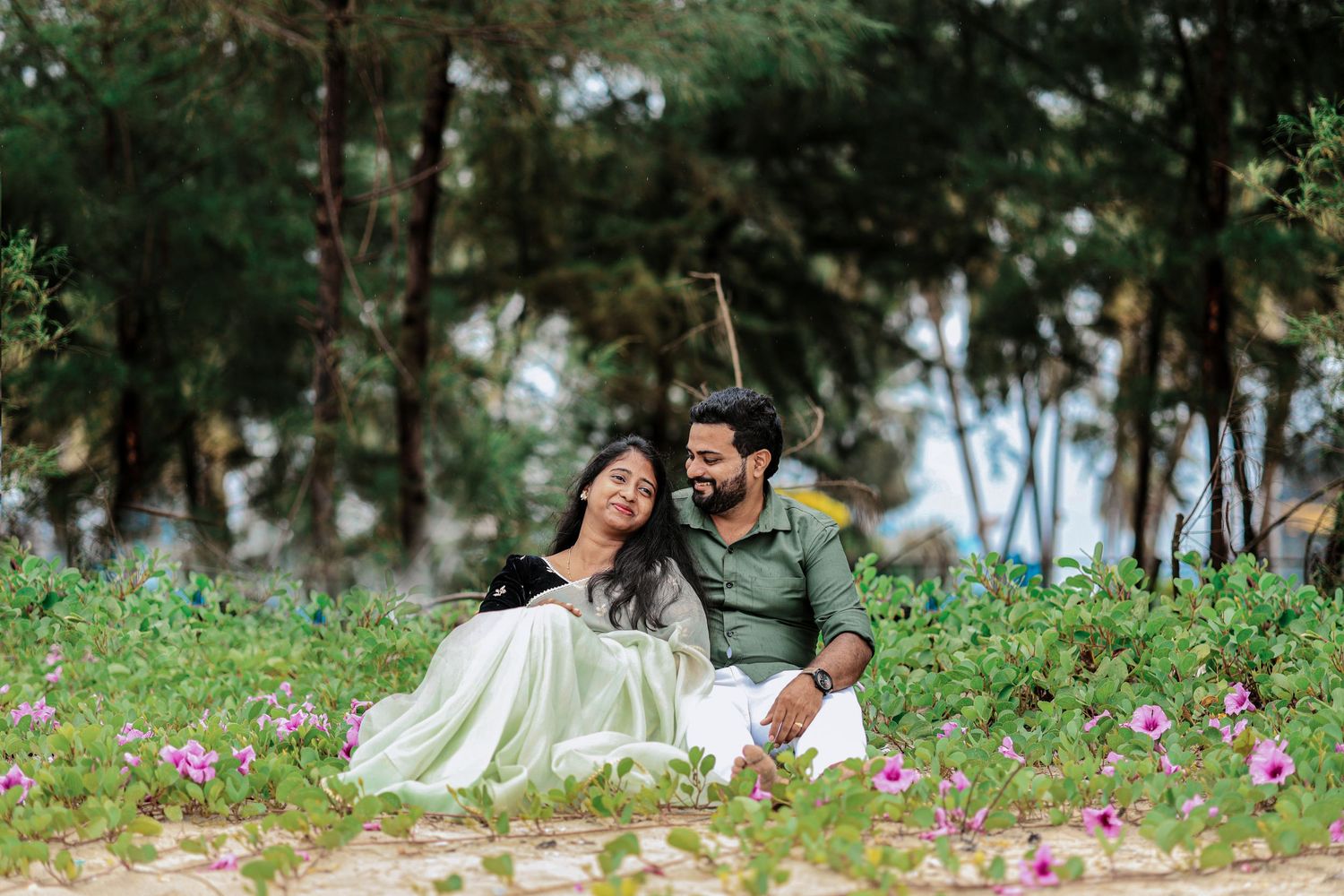 Couple sitting together among flowers during an outdoor photoshoot